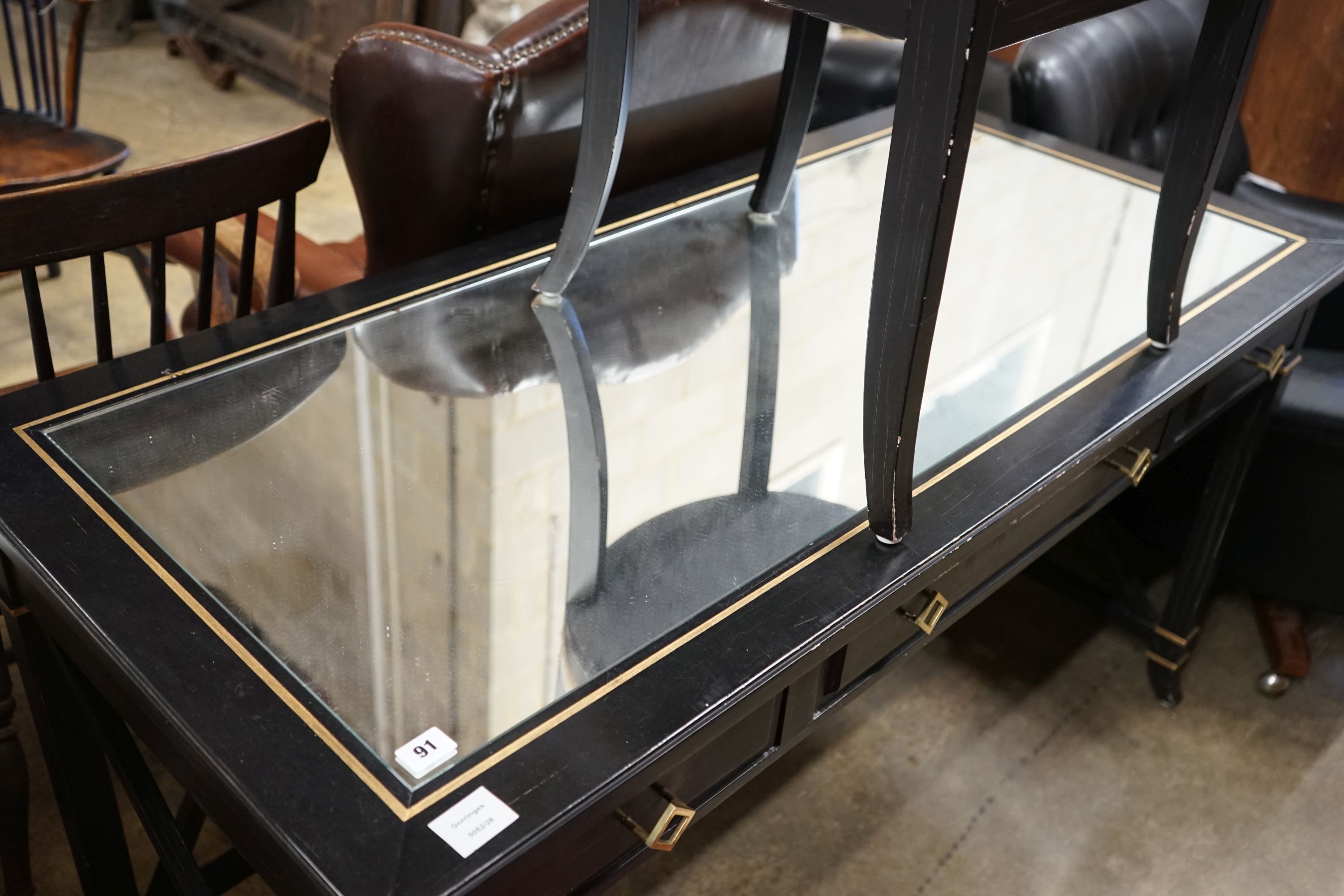 A painted mirrored three drawer ebonised writing table, length 140cm, depth 64cm, height 76cm together with a matching tub framed elbow chair
